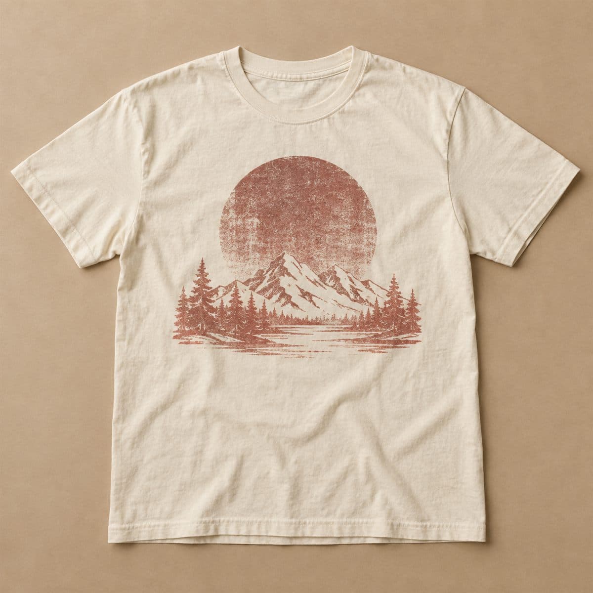 เสื้อยืดสีครีมวางแบน สกรีนพิกเมนต์ลายภูเขากับป่าสนใต้ดวงอาทิตย์สีอิฐ ผิวลายซีดแบบเสื้อเก่า